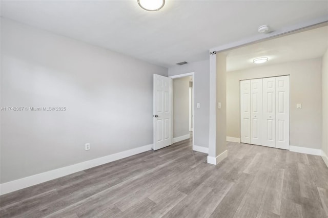 unfurnished bedroom with a closet and light wood-type flooring