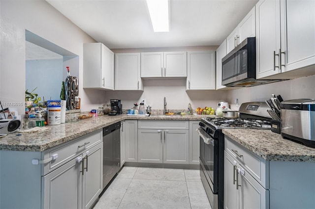 kitchen featuring light tile patterned flooring, sink, appliances with stainless steel finishes, kitchen peninsula, and light stone countertops