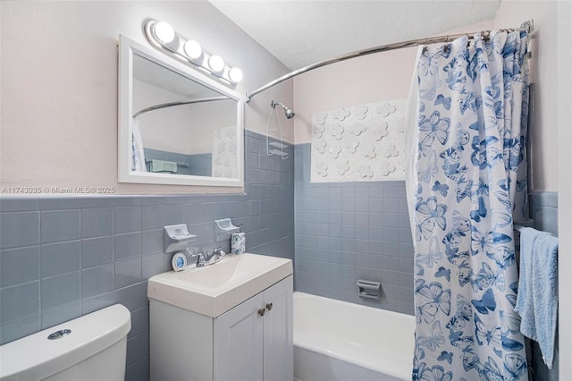 full bathroom with vanity, tile walls, shower / bath combo with shower curtain, and toilet