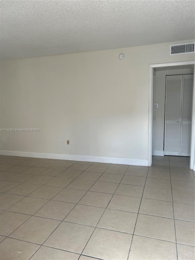 tiled empty room featuring a textured ceiling