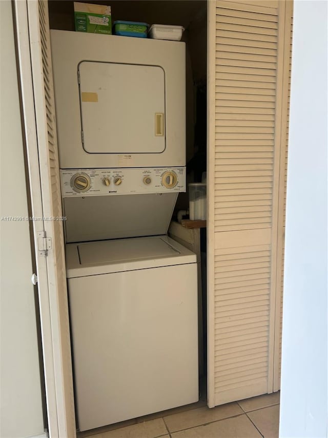 laundry area with light tile patterned flooring and stacked washer / drying machine