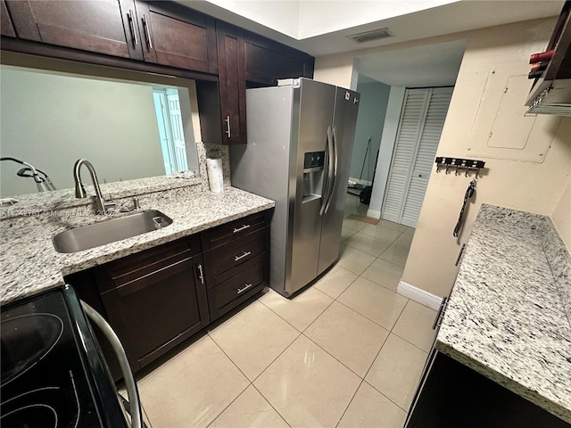 kitchen with stainless steel fridge with ice dispenser, sink, light stone countertops, and range with electric stovetop