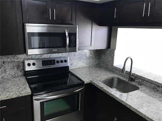 kitchen featuring light stone countertops, appliances with stainless steel finishes, sink, and decorative backsplash