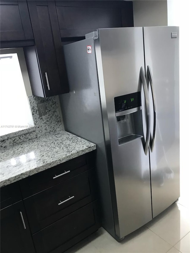 kitchen featuring light stone counters, decorative backsplash, and stainless steel fridge