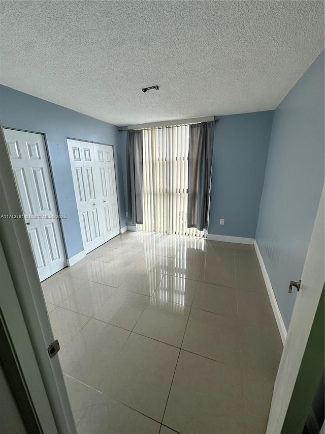 tiled spare room featuring a textured ceiling