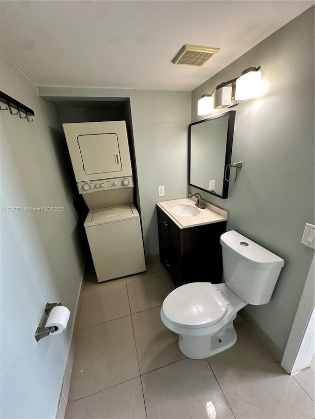 bathroom with toilet, tile patterned floors, vanity, and stacked washing maching and dryer