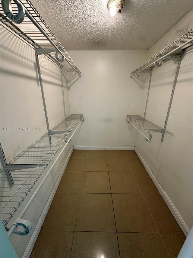 walk in closet featuring dark tile patterned floors