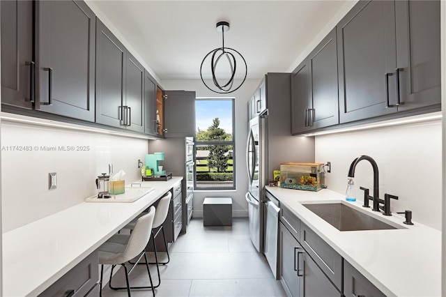 kitchen featuring light tile patterned flooring, stainless steel appliances, decorative light fixtures, and sink