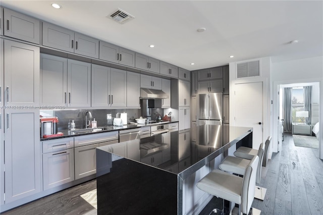 kitchen featuring stainless steel appliances, a center island, sink, and dark wood-type flooring