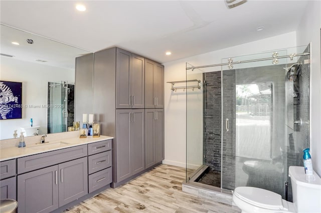 bathroom featuring vanity, wood-type flooring, a shower with door, and toilet