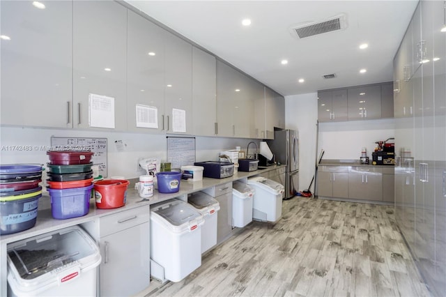 kitchen with stainless steel refrigerator, light wood-type flooring, and gray cabinetry