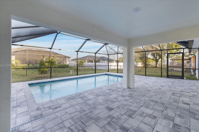 view of swimming pool featuring a yard, glass enclosure, and a patio area