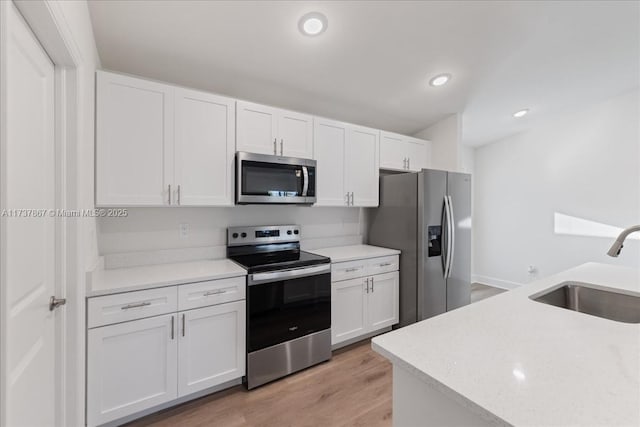 kitchen featuring white cabinetry, appliances with stainless steel finishes, sink, and light hardwood / wood-style flooring