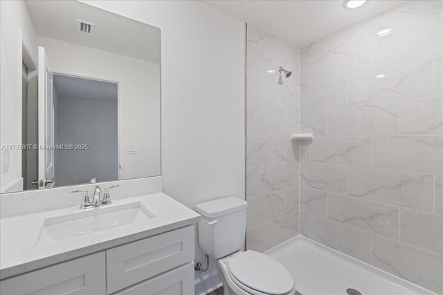 bathroom featuring vanity, toilet, and a tile shower