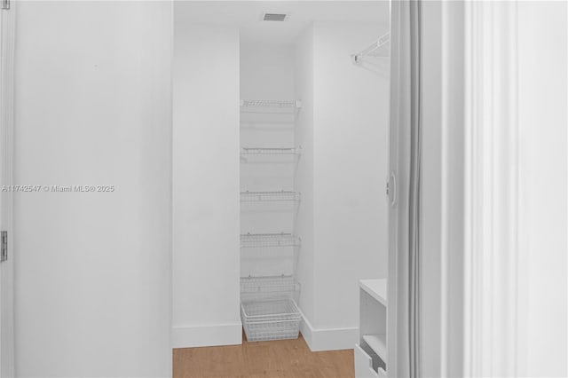 walk in closet with light hardwood / wood-style flooring