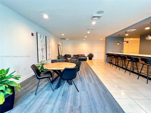 dining space with bar and light tile patterned floors