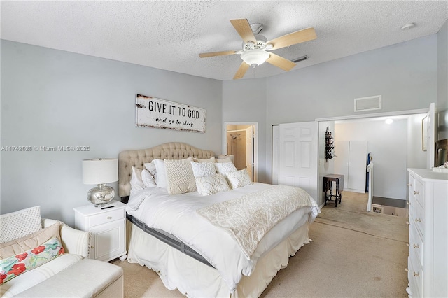 carpeted bedroom featuring ceiling fan and a textured ceiling