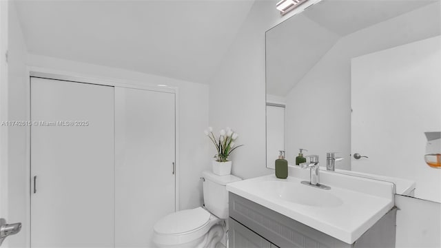 bathroom featuring vanity, lofted ceiling, and toilet