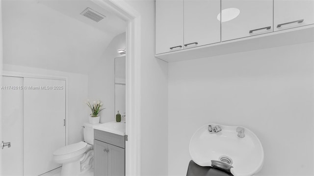 bathroom with vanity, vaulted ceiling, and toilet