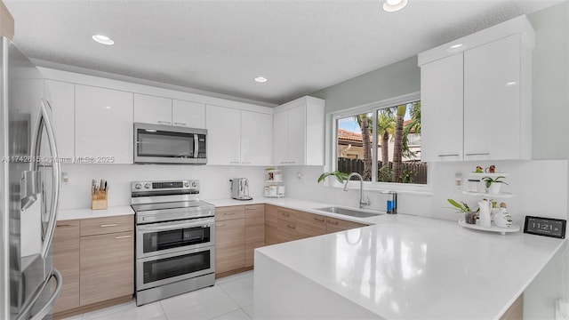 kitchen with white cabinetry, appliances with stainless steel finishes, kitchen peninsula, and sink