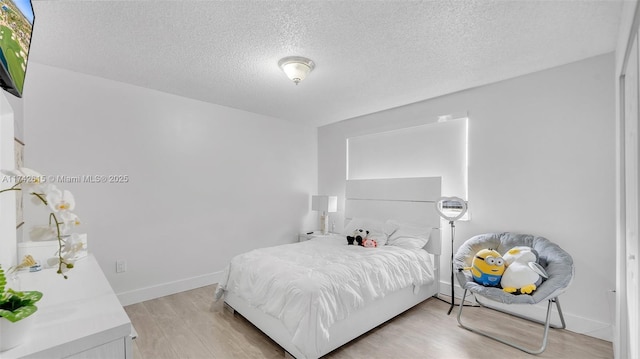 bedroom with a textured ceiling and light wood-type flooring