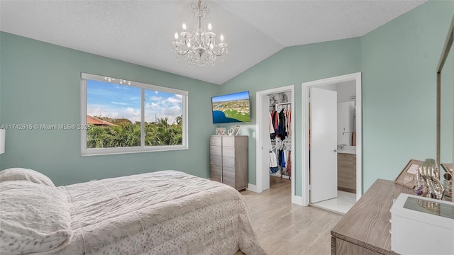 bedroom featuring lofted ceiling, light wood-type flooring, a walk in closet, a textured ceiling, and a closet