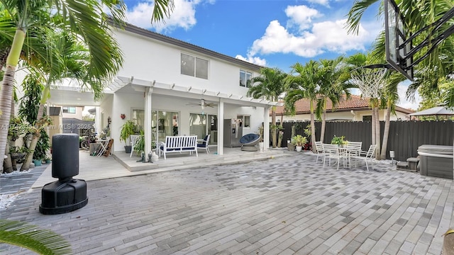 back of property with a pergola, a hot tub, and ceiling fan