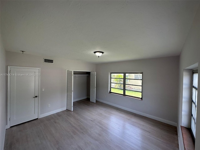 unfurnished bedroom with a textured ceiling, light hardwood / wood-style floors, and a closet