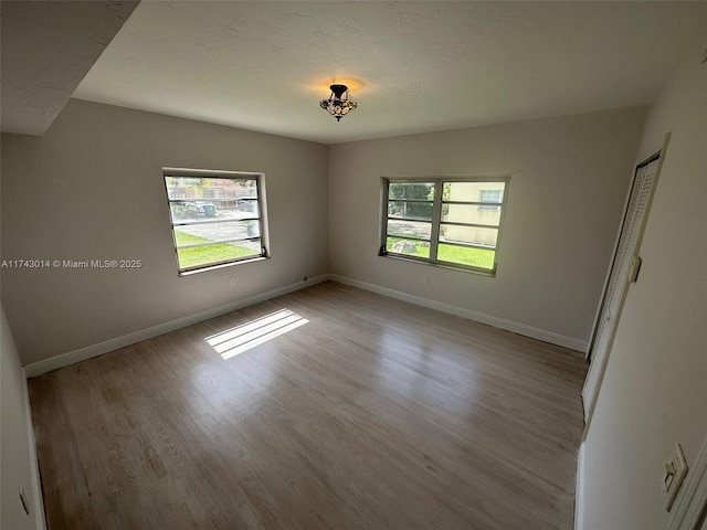 unfurnished room with light hardwood / wood-style floors and a textured ceiling