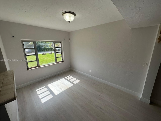 unfurnished room featuring light hardwood / wood-style flooring and a textured ceiling