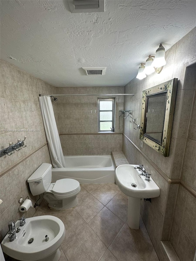 full bathroom with toilet, a textured ceiling, a bidet, shower / bathtub combination with curtain, and tile patterned flooring