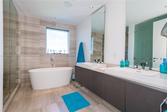 bathroom with vanity, a bathtub, and tile walls