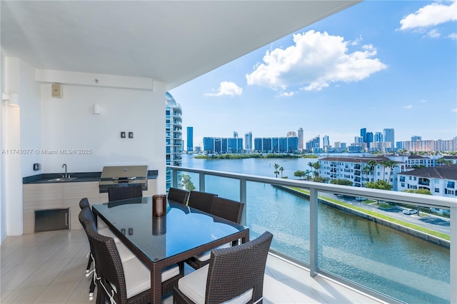 balcony featuring exterior kitchen, a water view, sink, and grilling area