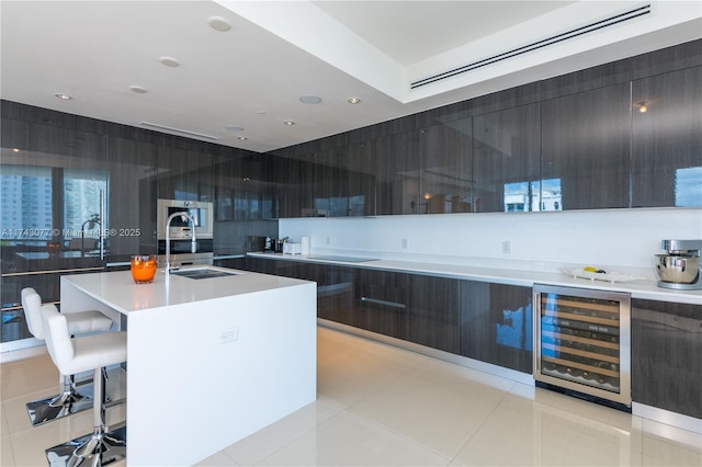 kitchen with sink, wine cooler, a kitchen breakfast bar, a kitchen island with sink, and light tile patterned floors