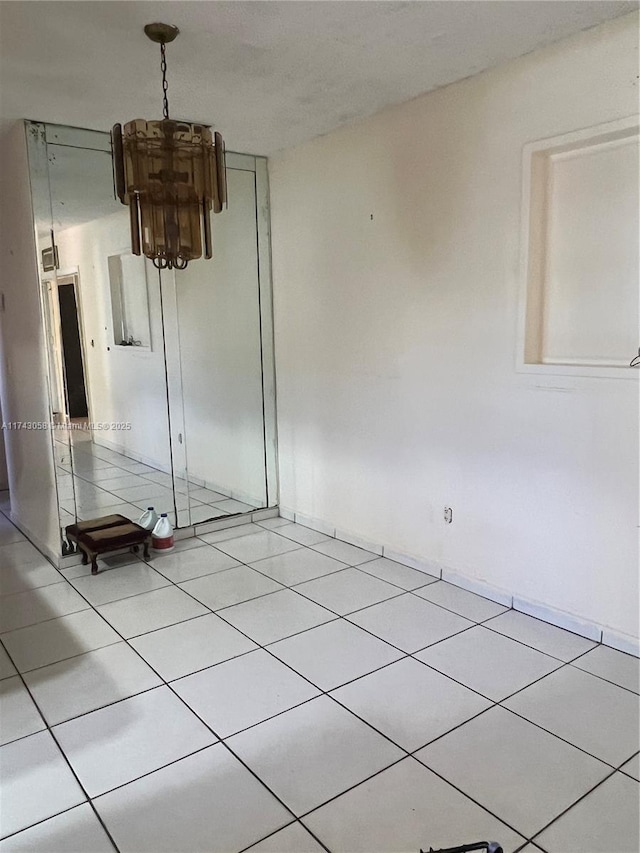 spare room with light tile patterned flooring and an inviting chandelier