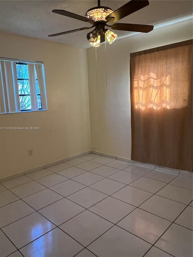 spare room with light tile patterned flooring, ceiling fan, and a textured ceiling