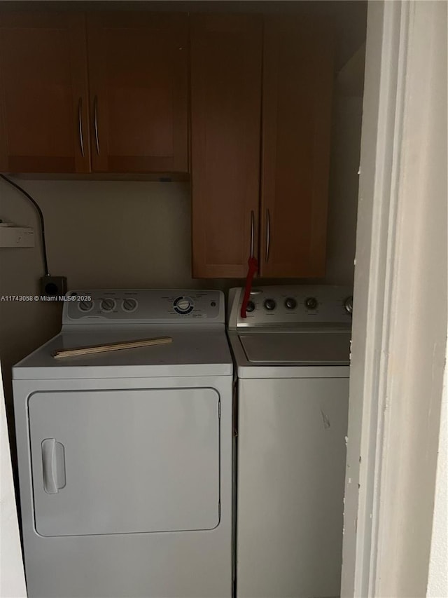 laundry room with separate washer and dryer and cabinets