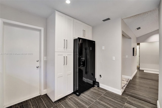 kitchen featuring white cabinetry and black fridge with ice dispenser