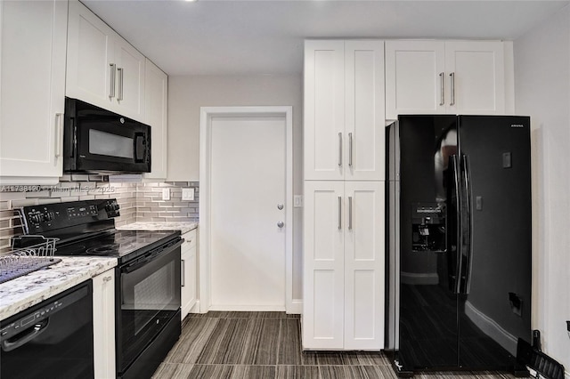 kitchen with white cabinetry, light stone countertops, decorative backsplash, and black appliances