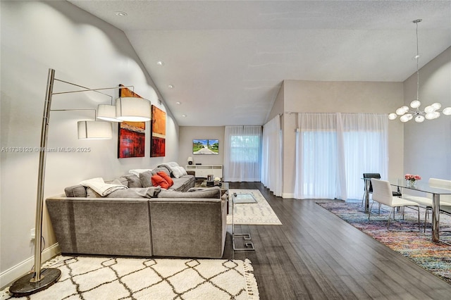 living room featuring vaulted ceiling, hardwood / wood-style floors, and a chandelier