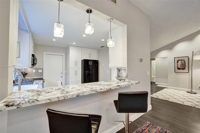 kitchen featuring tasteful backsplash, white cabinetry, dark hardwood / wood-style flooring, hanging light fixtures, and black appliances