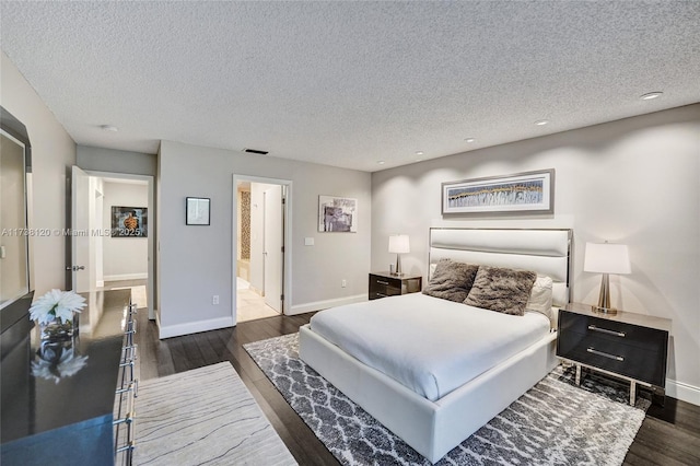 bedroom featuring ensuite bath, dark wood-type flooring, and a textured ceiling