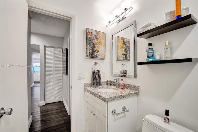 bathroom featuring vanity, hardwood / wood-style floors, a textured ceiling, and toilet