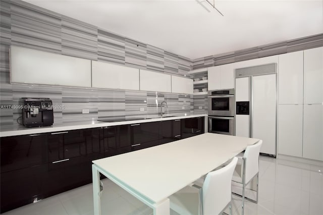 kitchen featuring white cabinetry, light tile patterned floors, paneled built in fridge, stainless steel double oven, and black electric cooktop