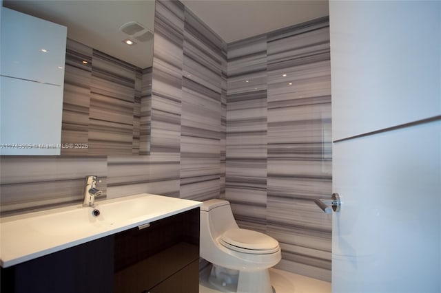 bathroom with vanity, tile walls, and toilet