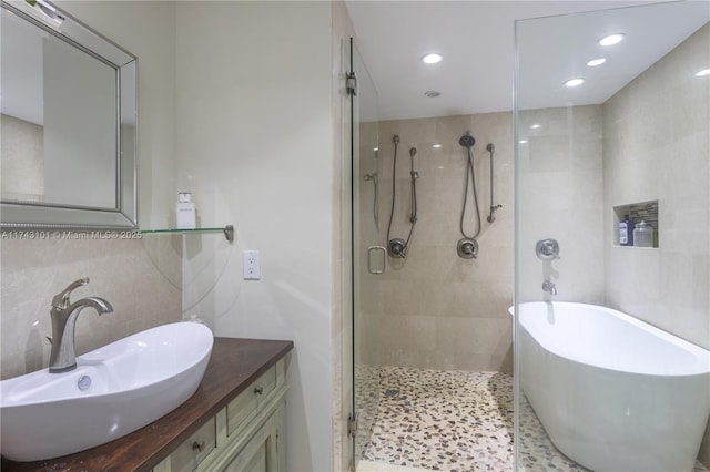 bathroom with backsplash, tile walls, independent shower and bath, and vanity