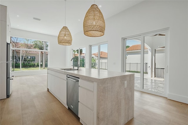 kitchen featuring white cabinetry, hanging light fixtures, sink, and an island with sink