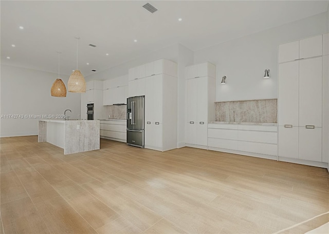 kitchen with pendant lighting, white cabinetry, high end refrigerator, a large island, and light wood-type flooring