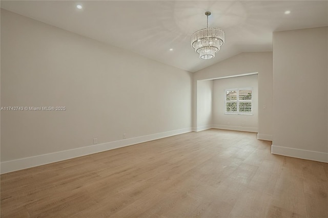 empty room featuring light hardwood / wood-style flooring, vaulted ceiling, and a chandelier