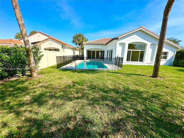 rear view of house with a fenced in pool, a patio, and a lawn